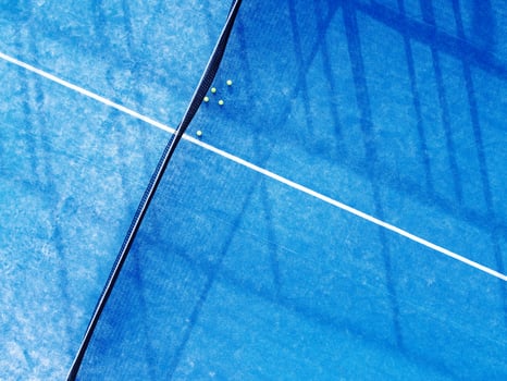 Abstract top-down aerial view of a blue padel court with net and balls. photo