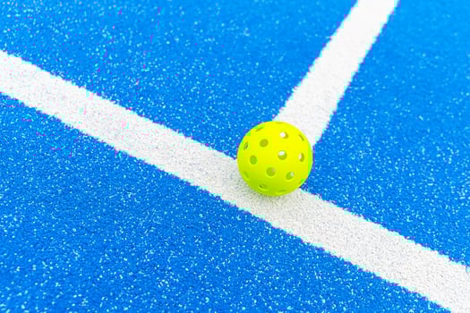 A close up of a plastic ball with holes used for playing pickleball sports equipment concept photo