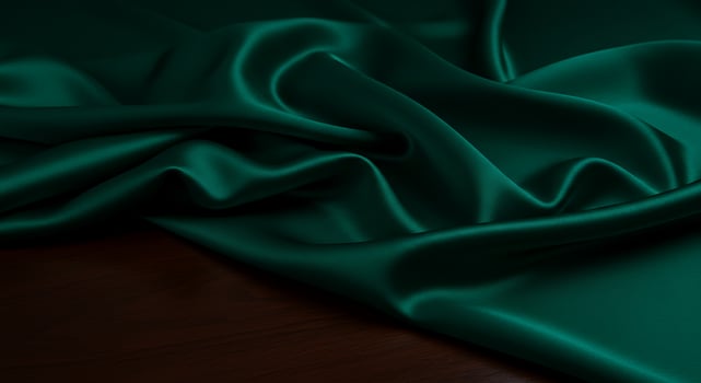Elegant Dark Green Satin Fabric Draped Over Wooden Surface in Soft Lighting photo