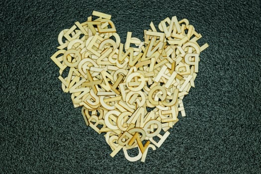 Wooden English letters arranged into heart on black textured carpet photo