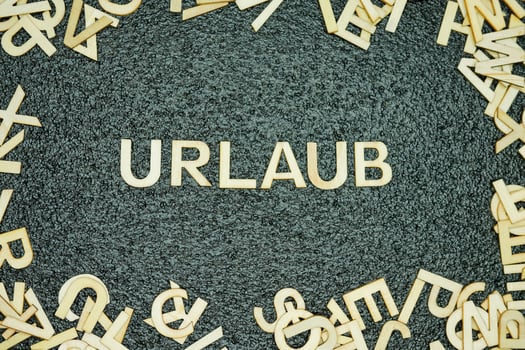 Wooden letters spelling urlaub on black rubber textured mat photo