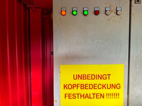 Metal wall with large yellow warning sign and colorful control buttons photo