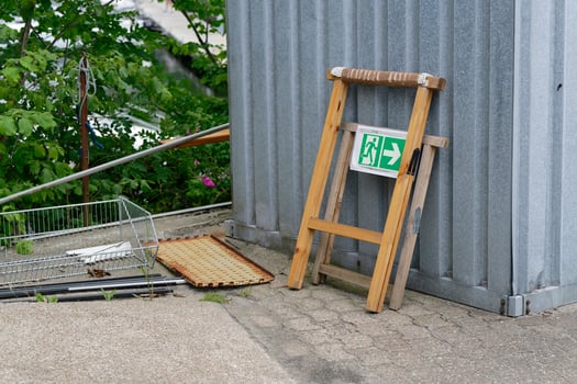 Metal container with wooden signs and scattered scrap metal nearby photo