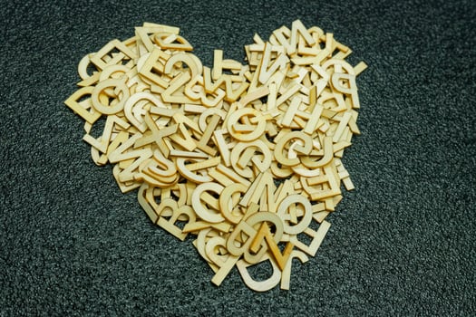 Scattered wooden alphabet letters and heart shape on dark black carpet photo
