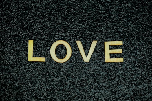 Wooden letters spelling love on black rubber textured surface photo
