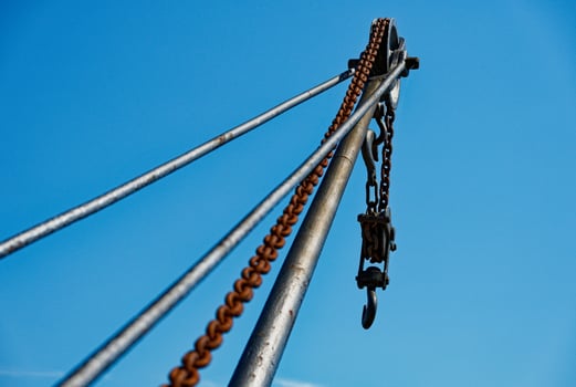 Industrial crane with weathered chain and hook under blue sky in Copenhagen CPH harbor photo