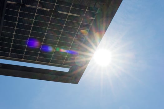 Bright sun with vivid rays and colorful light flares in clear sky over a solar panel solar cells photo