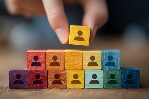 Hand placing yellow person icon block on colorful stack, symbolizing human resources, teamwork, and recruitment. photo