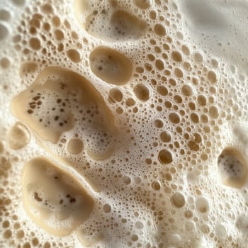 Beige colored foam with air bubbles presents a unique textural and detailed perspective photo