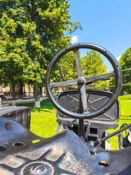 A black steering wheel with a white circle on it. The image has a mood of nostalgia and a sense of history photo