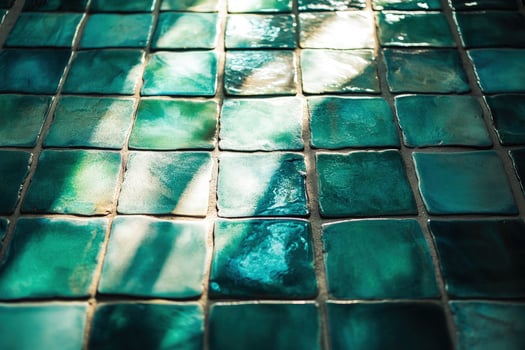 Light highlights textured turquoise tiles arrayed in a grid pattern showing a vibrant, artistic surface photo