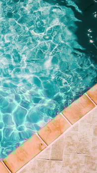 Sparkling turquoise water laps against the textured brick edge of a swimming pool photo