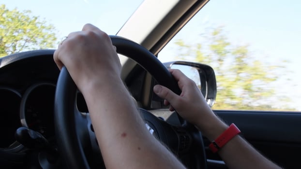 Male hands at steering wheel inside car photo