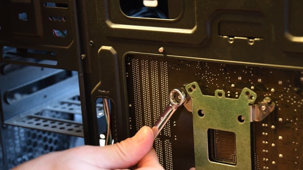 Fingers with metal wrench fix nut on bolt at computer motherboard photo