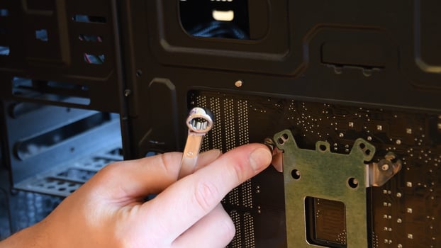 Hand with metal wrench fix nut on bolt at computer motherboard photo