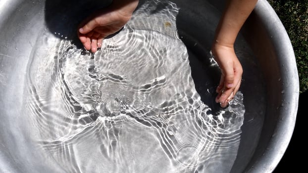 Toddler hands trying to collect clear water in handful playing water games photo