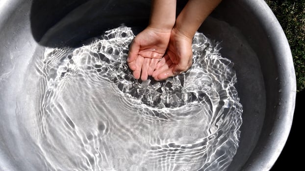 Toddler hands collect clear water in handful playing water games photo