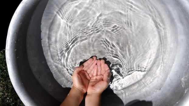 Kid hands collect clear water in handful while summer games photo