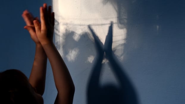 Shadows of kid clapping hands on stucco wall surface with copy space. Halloween concept photo