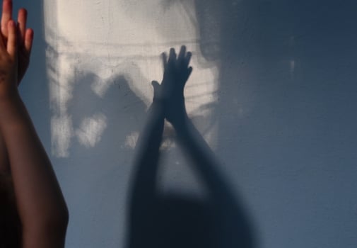 Defocused shadows of kid clapping hands on stucco wall surface with copy space. Halloween concept photo