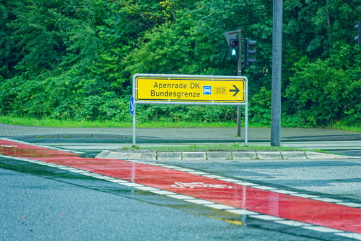 Road turn with red bike lane and traffic sign to Apenrade DK photo