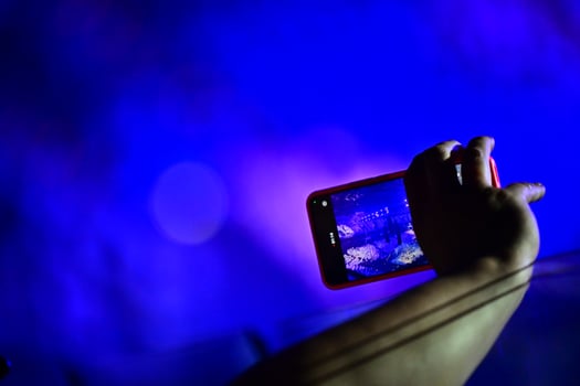 Phone recording a concert in pink neon light by a young hand photo
