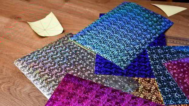 Sheets of colorful metallic paper mess atop wooden table surface photo