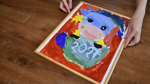 Hands put wooden picture frame at kids painting photo
