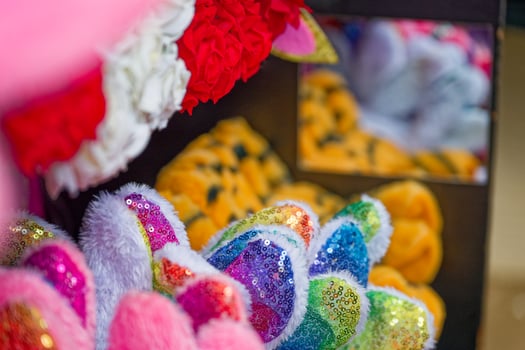 Colorful slippers with ears and bows displayed near a mirror in store photo
