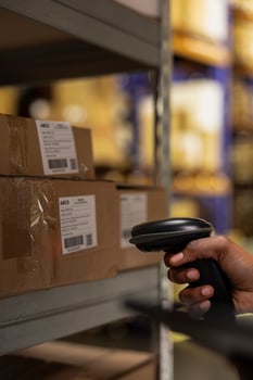 Close up of industrial depot worker scanning parcel details using tracking software, walking near huge storage racks. E-commerce delivery management system ensures accuracy in order processing. photo