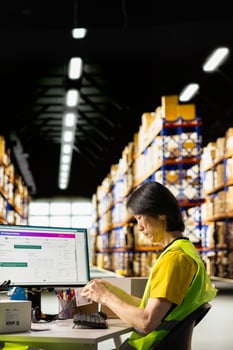 Logistics worker printing and applying awb labels on packages, wearing hi vis vest in a warehouse with barcode airway bill and shipping labels, ensuring order fulfillment and inventory tracking. photo