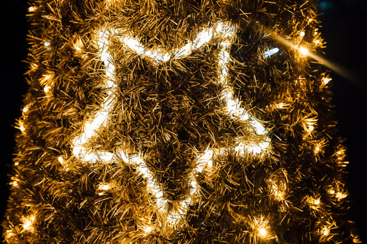 Bright golden star decoration on a festive tree during the holiday season at night photo