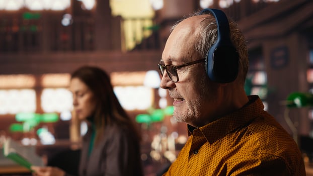 Elderly student breaking library rules with loud music on headset, dancing and singing in the campus library. Aged man receiving noise complaint from other people, disturbance. photo