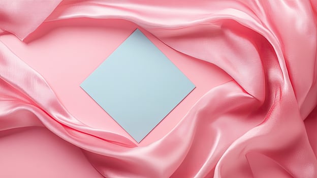 Wavy pink fabric elegantly frames the light blue square on a pink backdrop photo