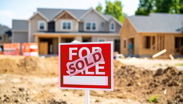 Sold sign in front of new homes under construction, showcasing vibrant real estate market. sign indicates successful sale amidst ongoing development photo