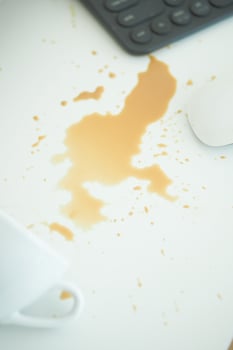 Coffee spill on white table with office supplies nearby photo