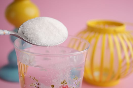 Mixing sugar into a clear glass of water at home photo