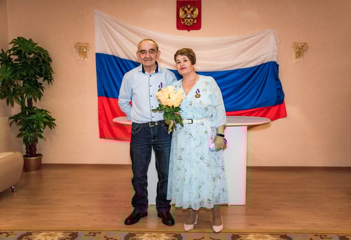 Senior Russian 75 years old couple celebreating golden wedding or 50 years wedding anniversary in marriage registry, Russian inscriptions of their medals say 50 years wedding anniversary photo