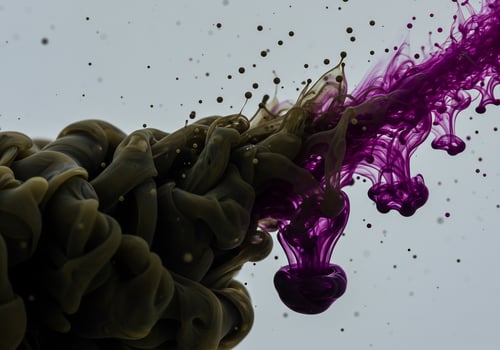 Vibrant Purple Ink Erupts from a Murky Green Cloud with Floating Droplets photo