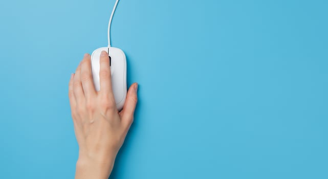 A person's hand holding a computer mouse on a blue background photo