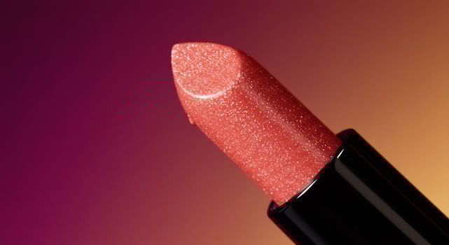 Radiant Coral Glitter Lipstick Against a Dramatic Magenta and Gold Gradient photo