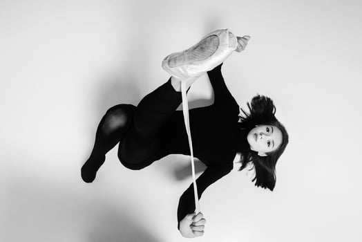 young ballerina in a black dress and total black sunglasses is lying on her back and tying pointe shoes photo