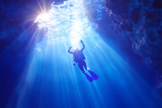 Scuba diver ascends in sunlit blue sea underwater adventure photo