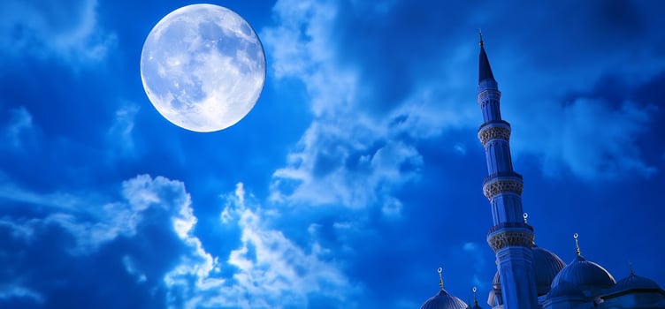 Nighttime building silhouette against moonlit blue sky photo