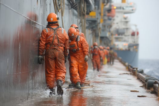 Workers in orange suits walking down the side of a ship photo