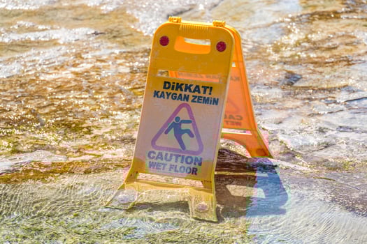 Yellow wet floor sign on a wet stone surface with turkey text. Safety warning for slippery conditions display at a travel destination. photo