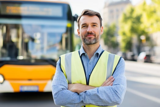 Man in safety vest posing in front of a public bus on city street daytime photo