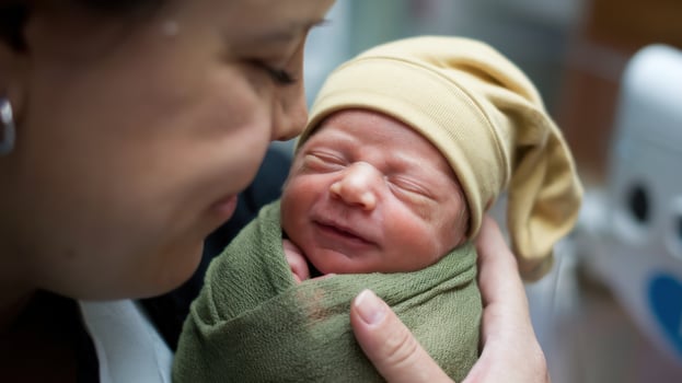 A woman holding a newborn in a hospital photo