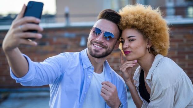man and woman taking selfie outdoors, enjoying sunny day photo