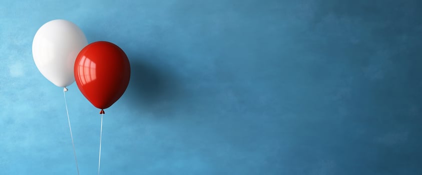 Red, white balloons float against blue wall photo